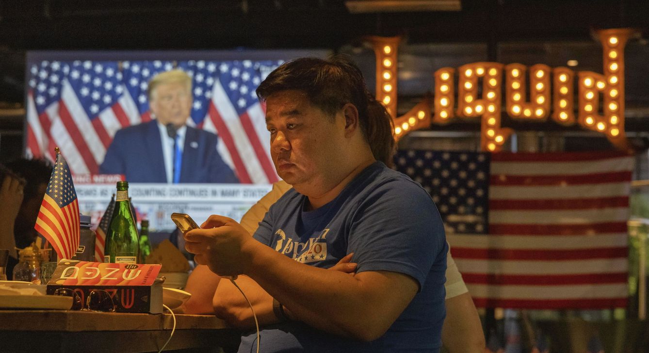 Varios hombres siguen el resultado de las elecciones estadounidenses en un bar de China. (EFE)