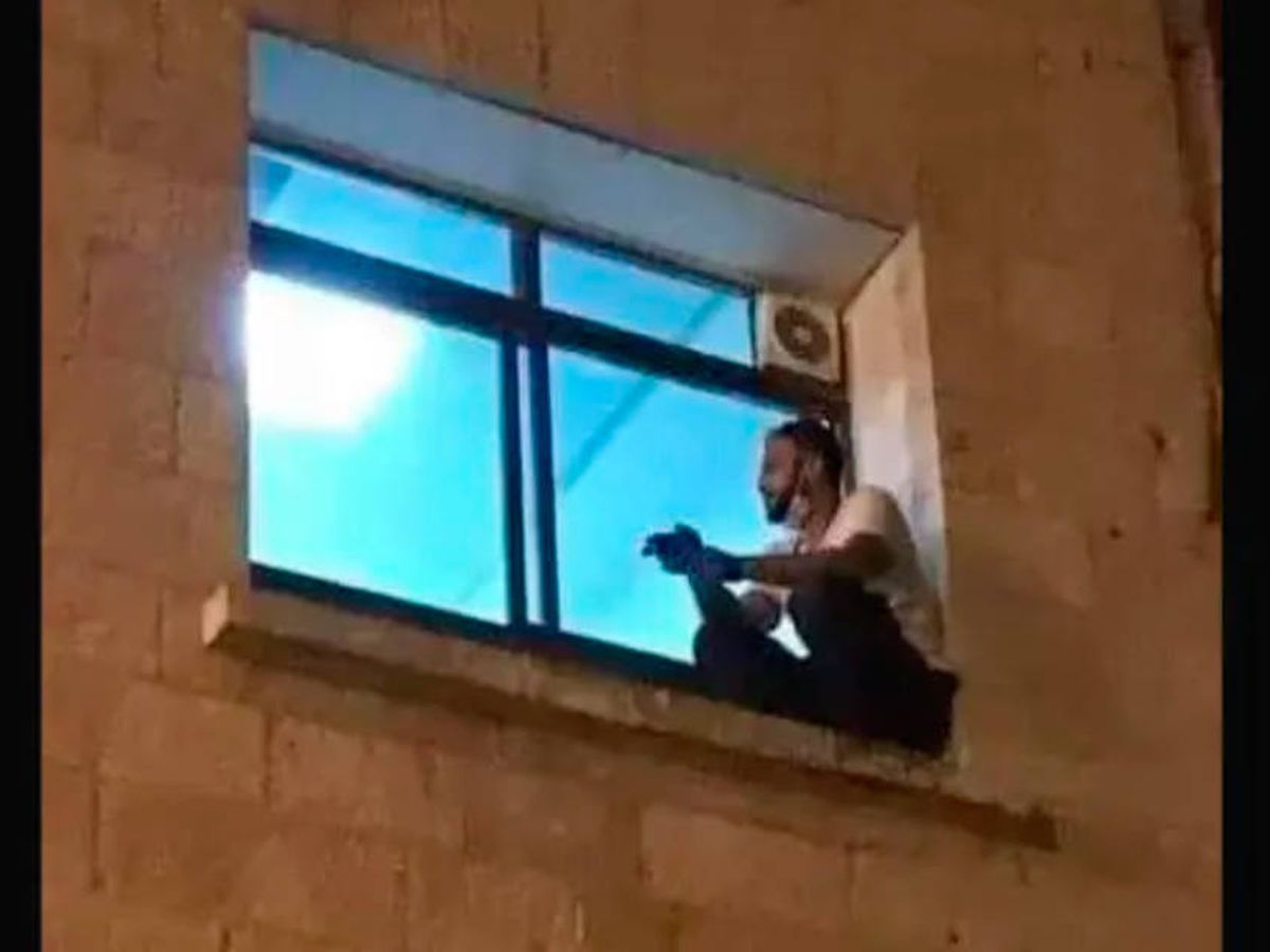 Foto: Jihad Al-Suwaiti, en el alféizar de la ventana del hospital donde estaba ingresada su madre (Foto: Twitter)