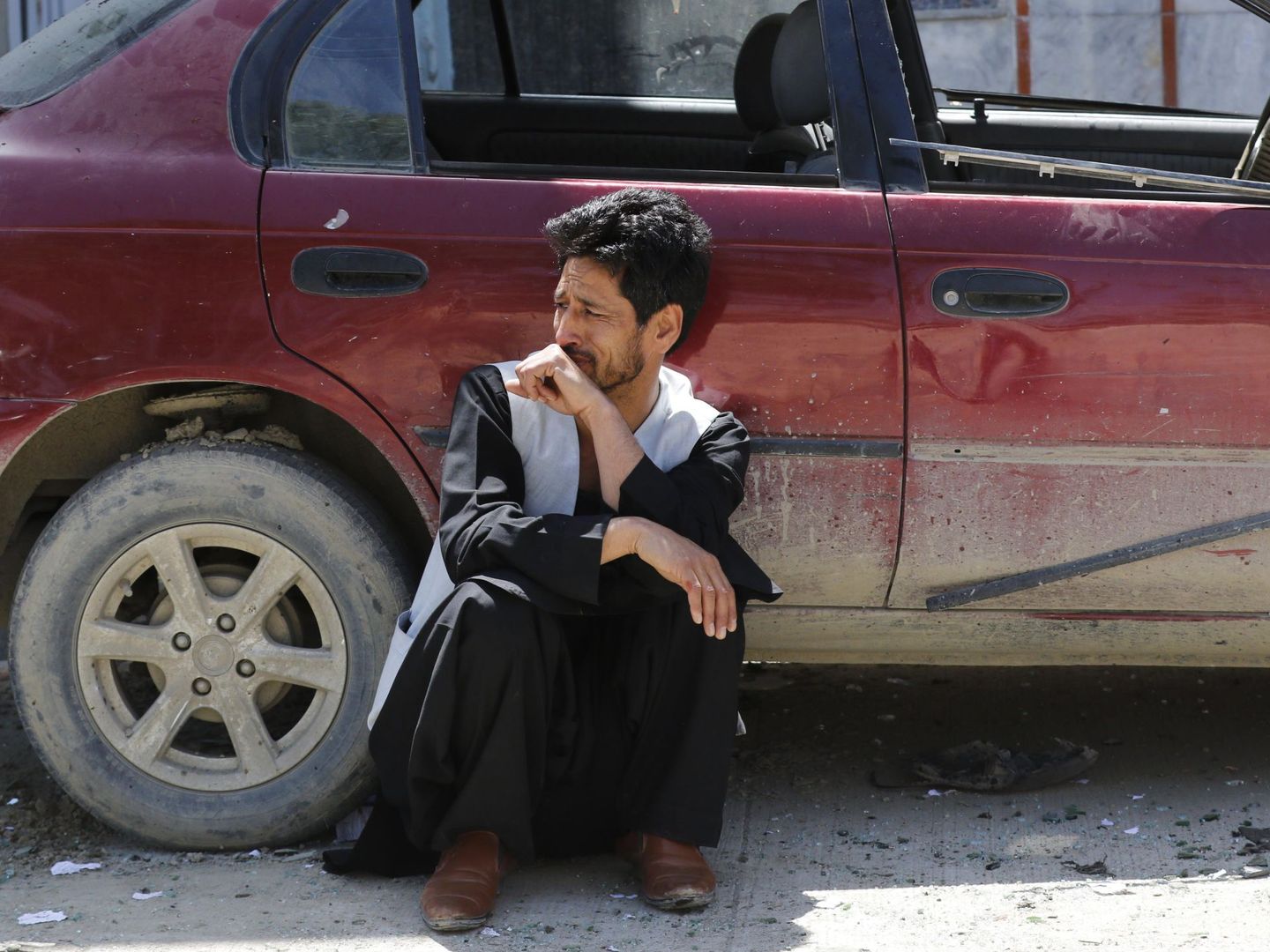 Un hombre llora sentado contra un coche tras el ataque. (Reuters)