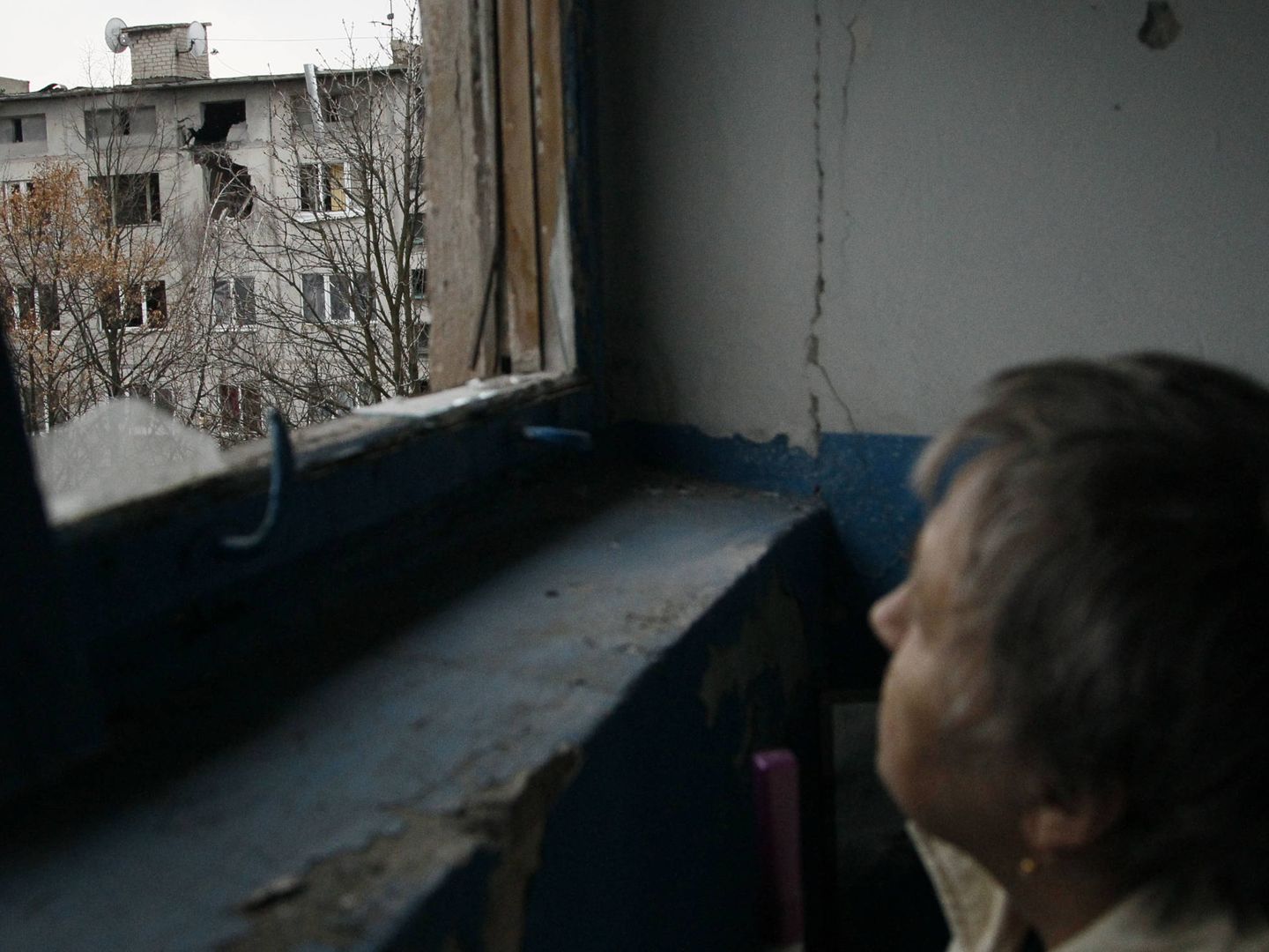 Una mujer observa un bloque de viviendas dañado por el fuego de artillería en Yasynuvata, Ucrania. (Reuters)