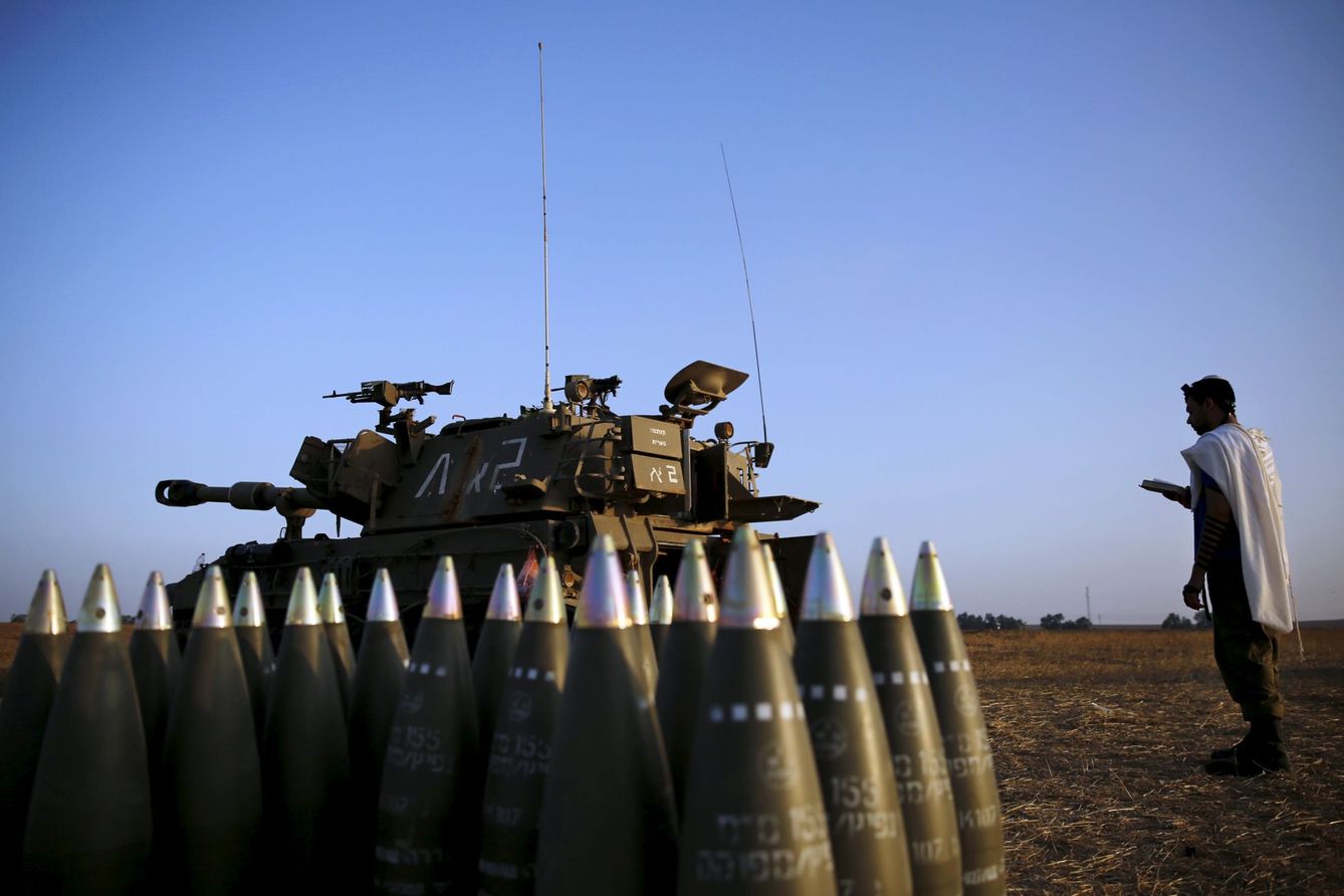 Un soldado israelí reza junto a una unidad de artillería móvil cerca de la Franja de Gaza en julio de 2014 (Reuters)