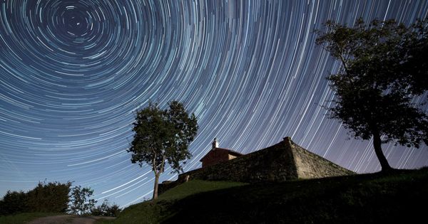 Foto: Imagen de larga exposición que muestra las estrellas circumpolares sobre la ermita de San Esteban, en Comillas, Cantabria. (EFE)