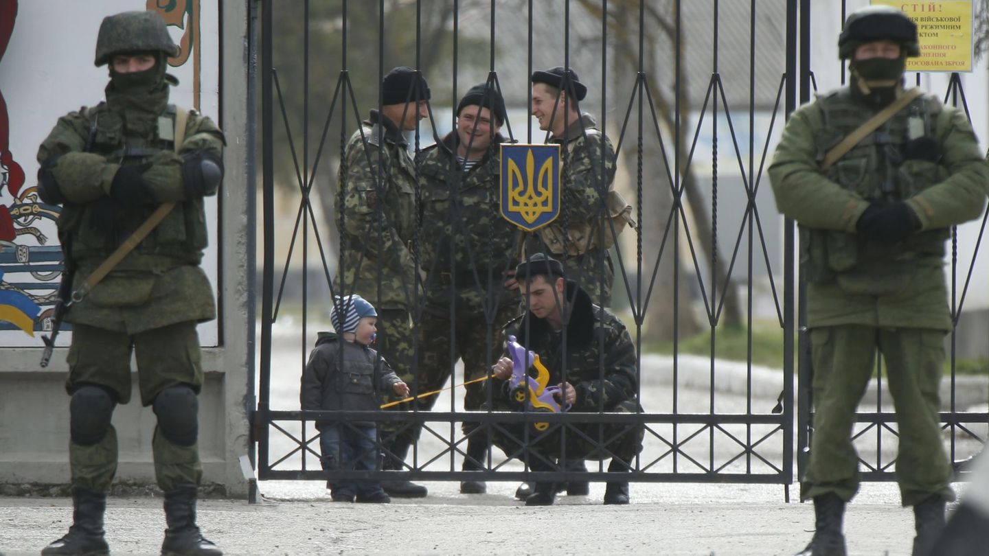 Un soldado ucraniano juega con un niño en un cuartel rodeado por rusos en Perevalnoye (Reuters).