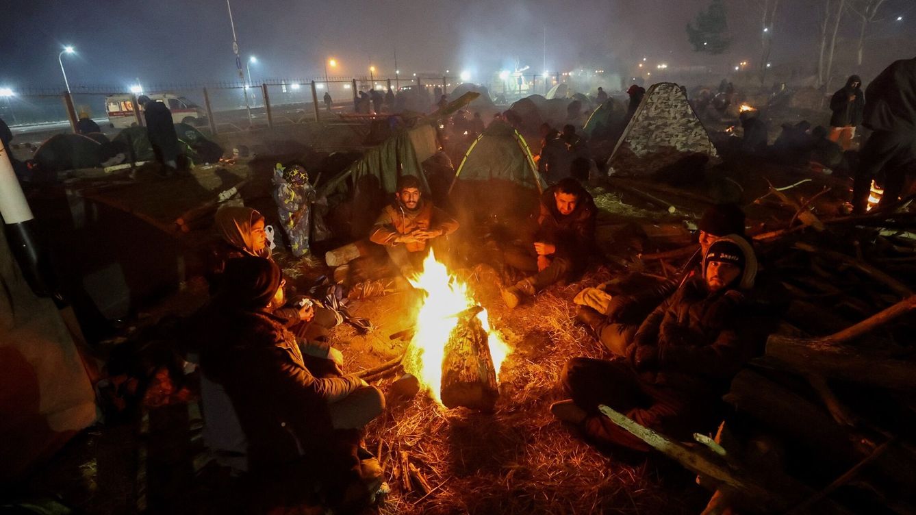 Foto: Migrantes se calientan frente a una hoguera en un campamento improvisado en la frontera entre Bielorrusia y Polonia. (EFE/Maxim Guchek)