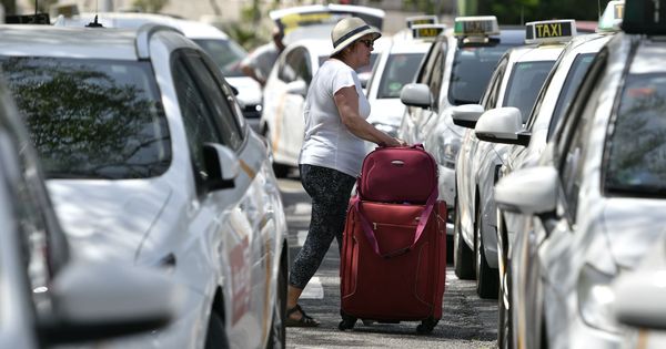 Foto: Una viajera pasa entre los taxis aparcados en Sevilla. (EFE)
