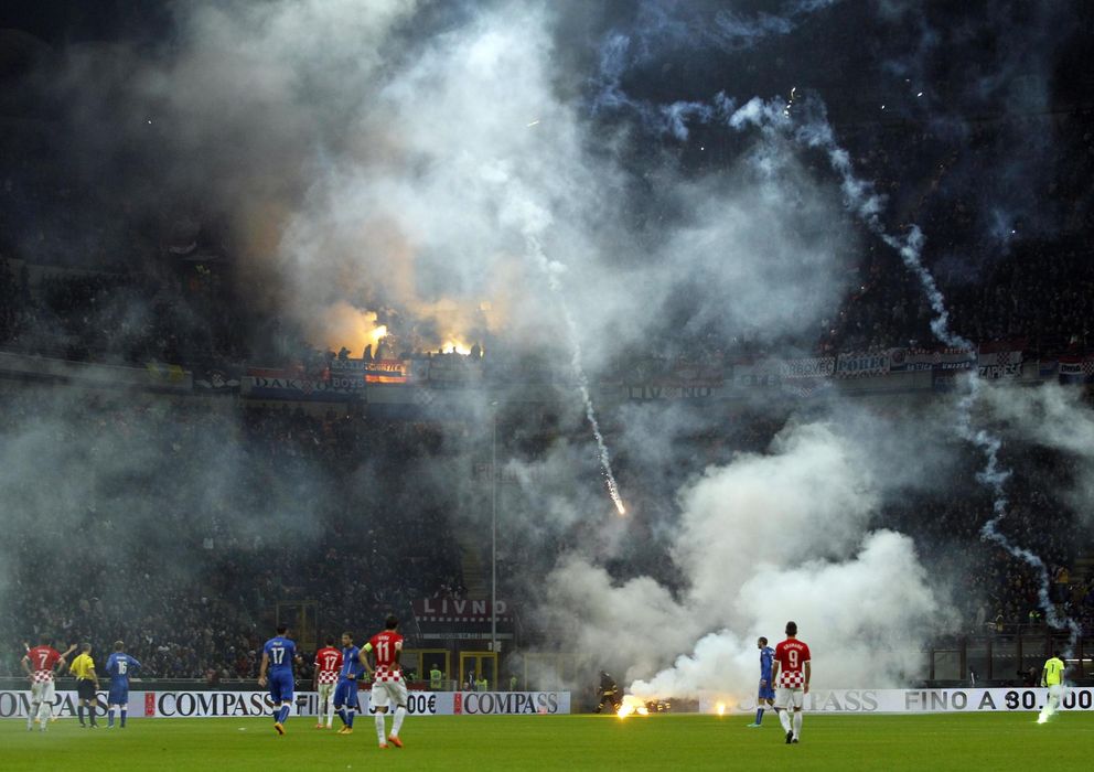 Foto: Los jugadores de Italia y Croacia observan impotentes la caída de bengalas sobre el césped del Meazza (Reuters).