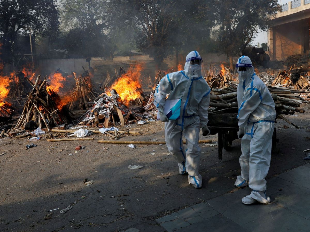 Foto: Trabajadores sanitarios incinerando los cuerpos de las víctimas fallecidas por coronavirus en Nueva Delhi. (Reuters)