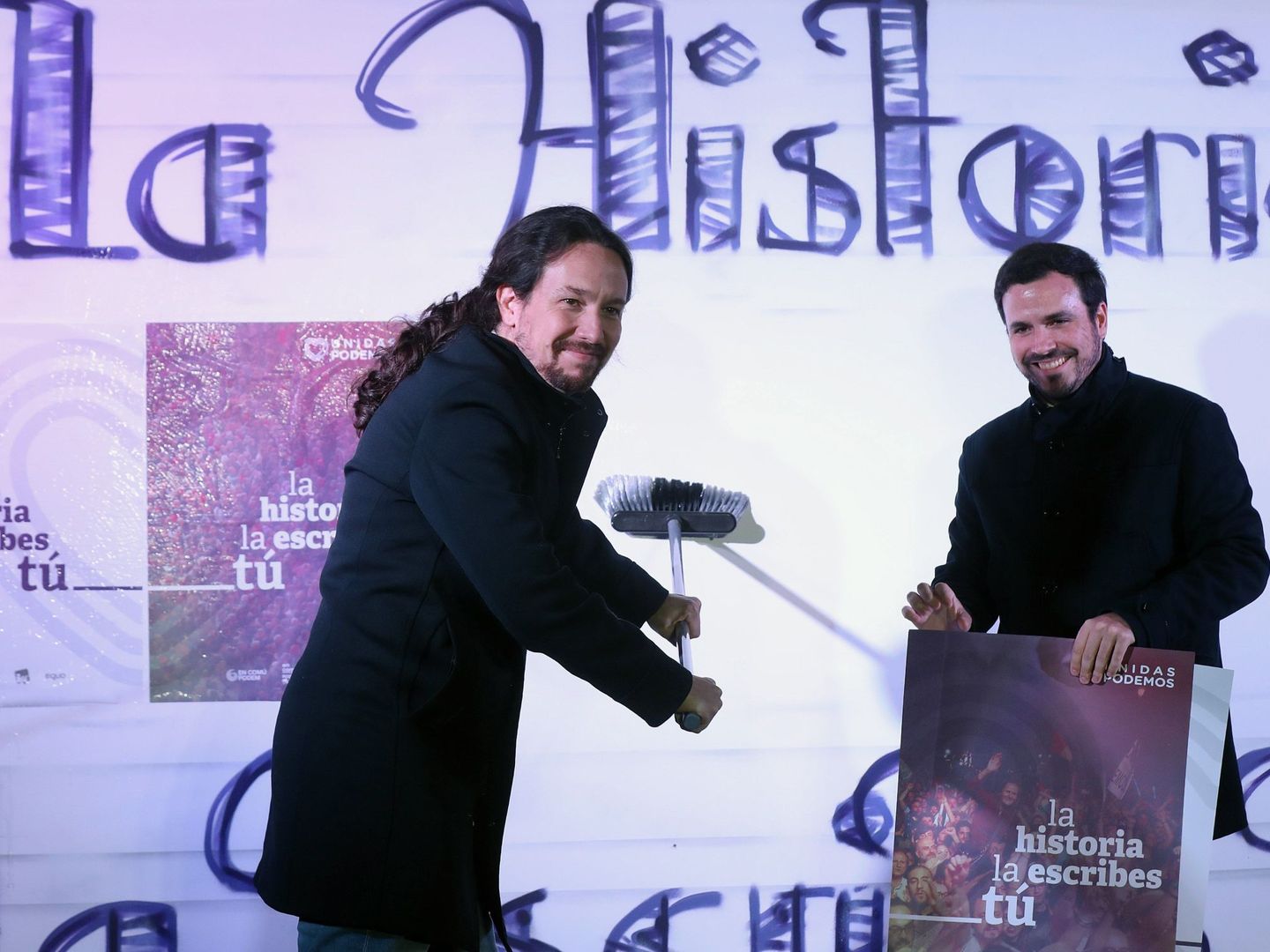 Pablo Iglesias (i) y Alberto Garzón, durante la tradicional pegada de carteles. (EFE)