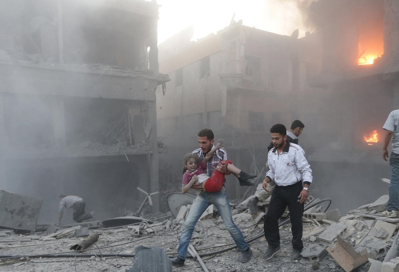 Un hombre rescata a una niña superviviente de un ataque aéreo del régimen de Asad en Douma, Damasco, en junio de 2015. (Reuters)