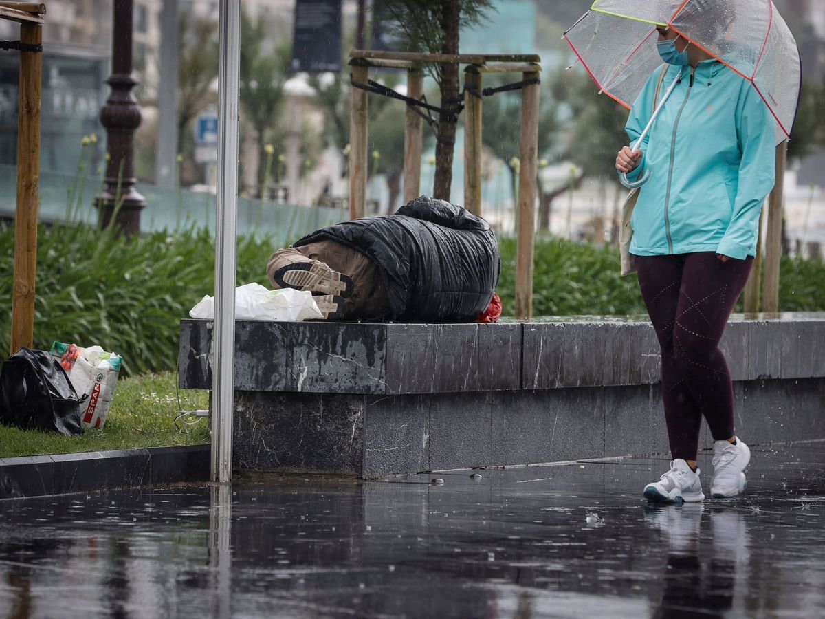 Foto: Un hombre sin hogar descansa en la calle bajo la lluvia en San Sebastián. (EFE)