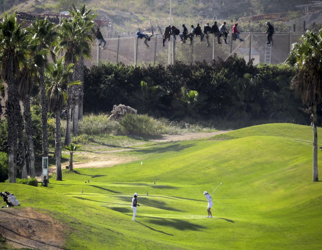 Un grupo de personas sobre la valla de Melilla (José Palazón/Reuters)