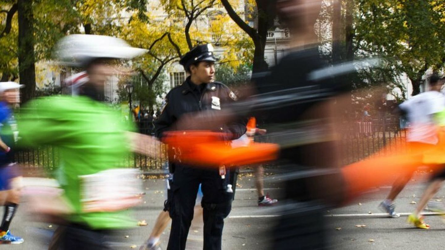 Nypd officer stands guard while runners make their way through the borough of manhattan during the new york city marathon