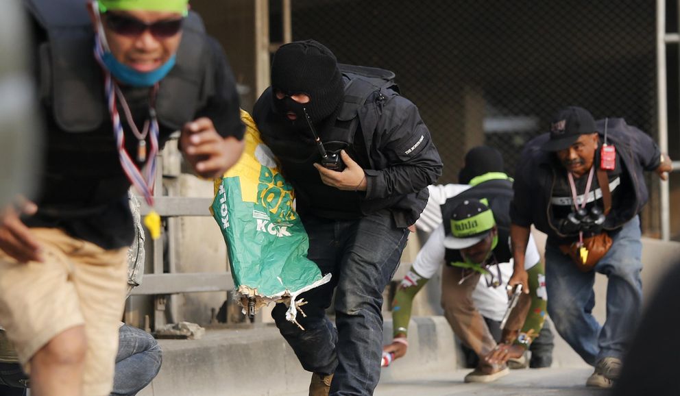 Opositores, uno con un rifle escondido bajo una bolsa,  corren durante un tiroteo en Bangkok (Reuters).