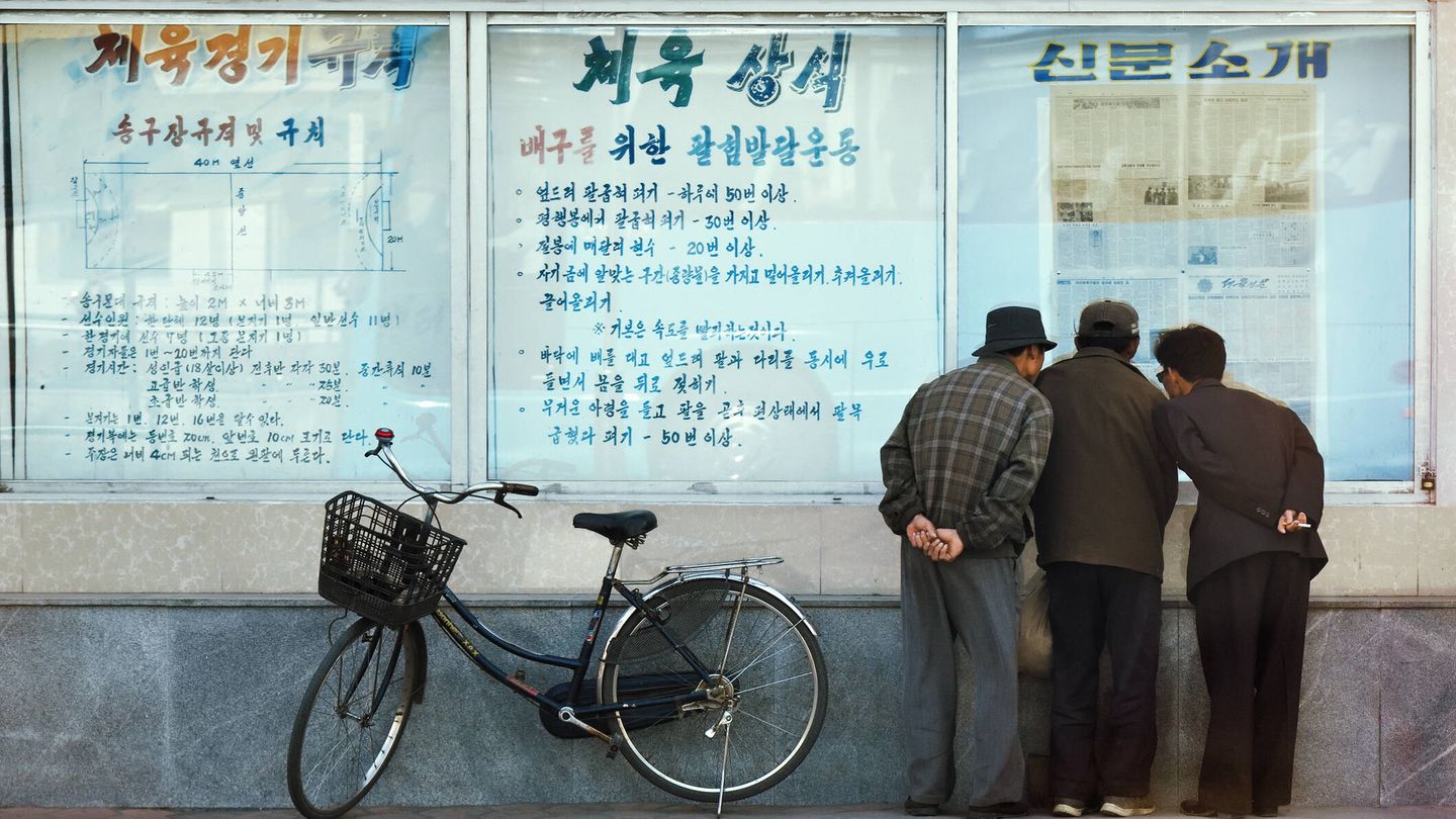 Tres hombres leen un periódico en Kaesong, Corea del Norte. (iStock)