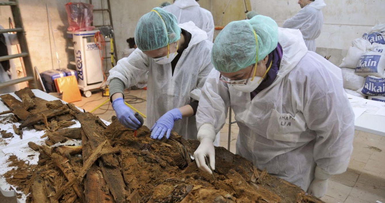Foto: Dos especialistas analizan parte de los restos hallados en la cripta de las trinitarias. (REUTERS)