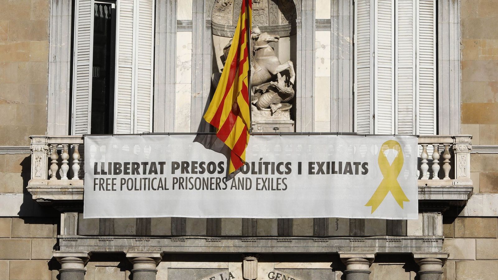 Foto: El cartel reclamando la libertad de los líderes independentistas presos y un lazo amarillo en la fachada del Palau de la Generalitat. (EFE)