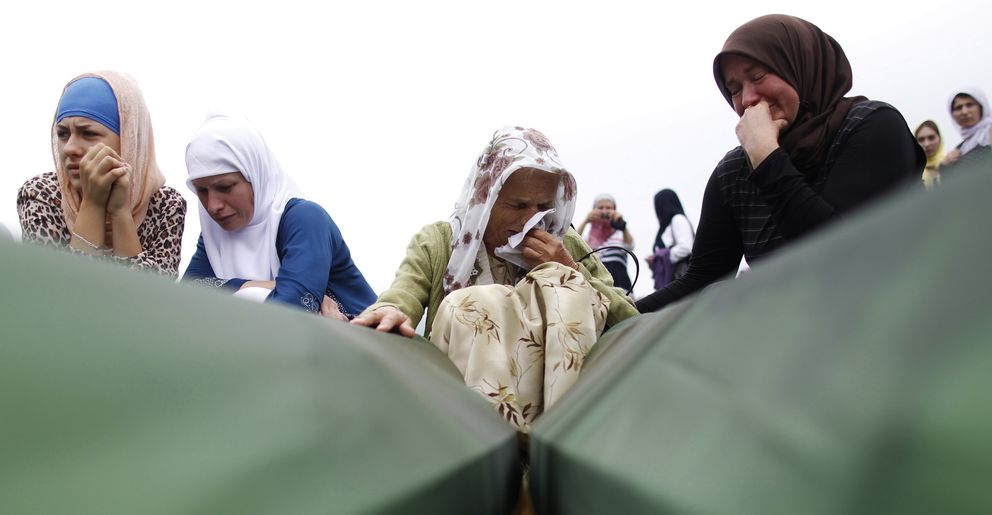 Mujeres bosnias lloran antes los ataúdes de sus familiares en Srebrenica (Reuters).