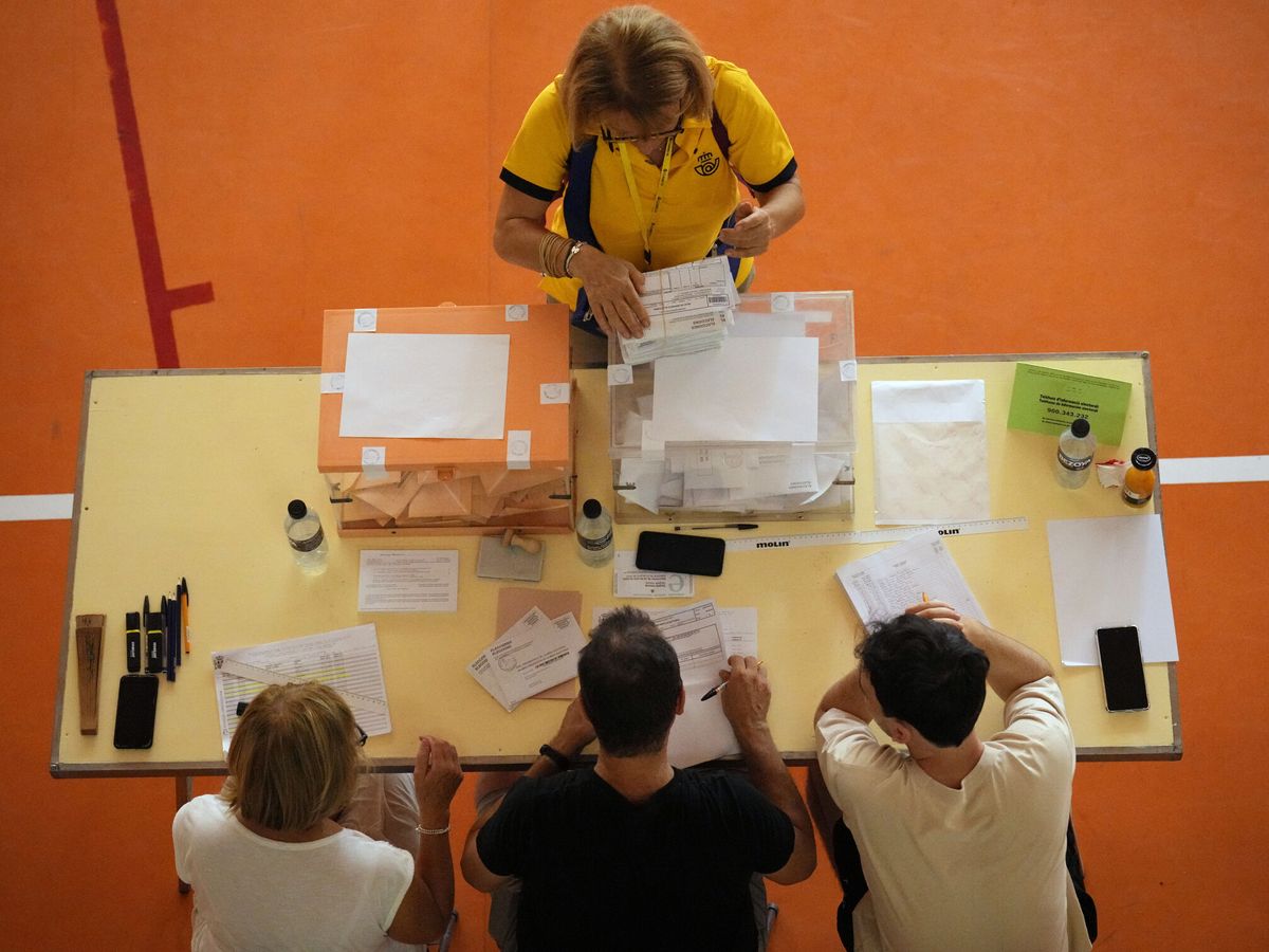 Foto: Una cartera entrega votos por correo en una mesa electoral en la escuela Grèvol en Barcelona. (EFE/Alejandro García)