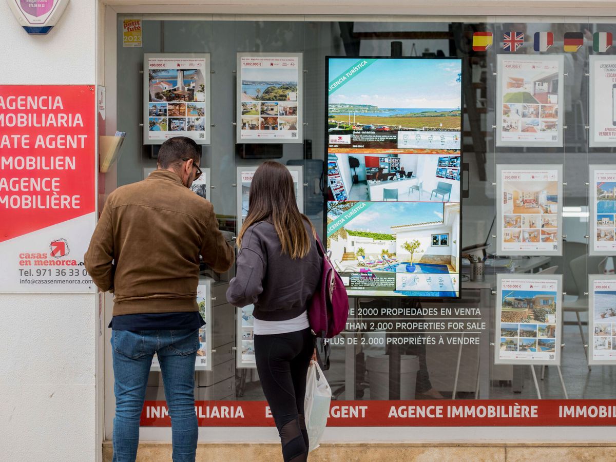 Foto: Dos personas observan el escaparte de una inmobiliaria en Menorca. (EFE/David Arquimbau Sintes)