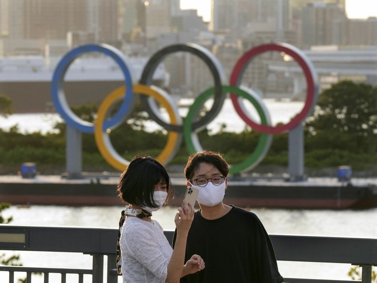 Foto: Una pareja frente a los anillos olímpicos, en la ciudad de Tokio. (Reuters)