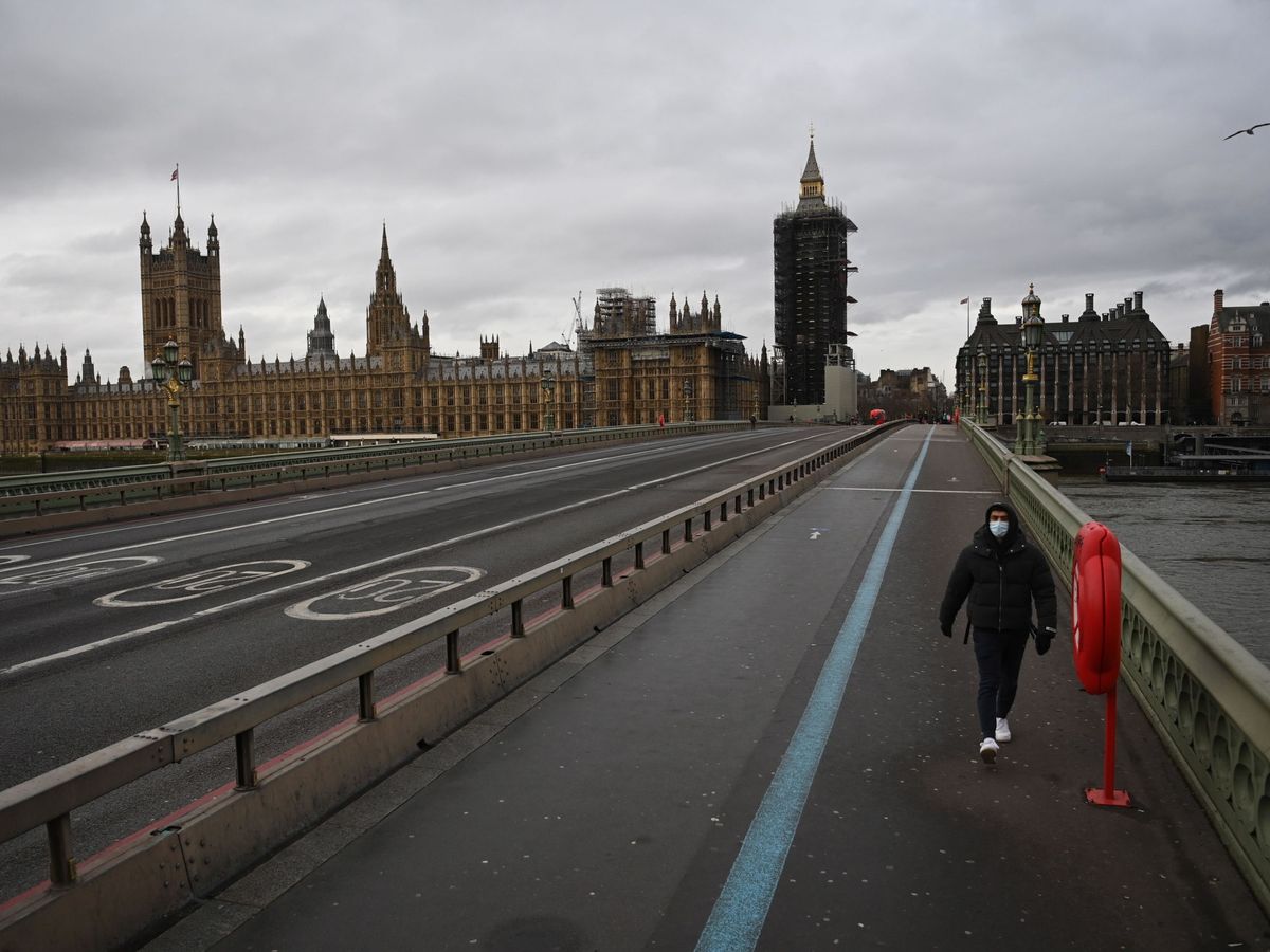 Foto: Un hombre camina frente al parlamento británico durante el primer día del tercer confinamiento estricto en Reino Unido.