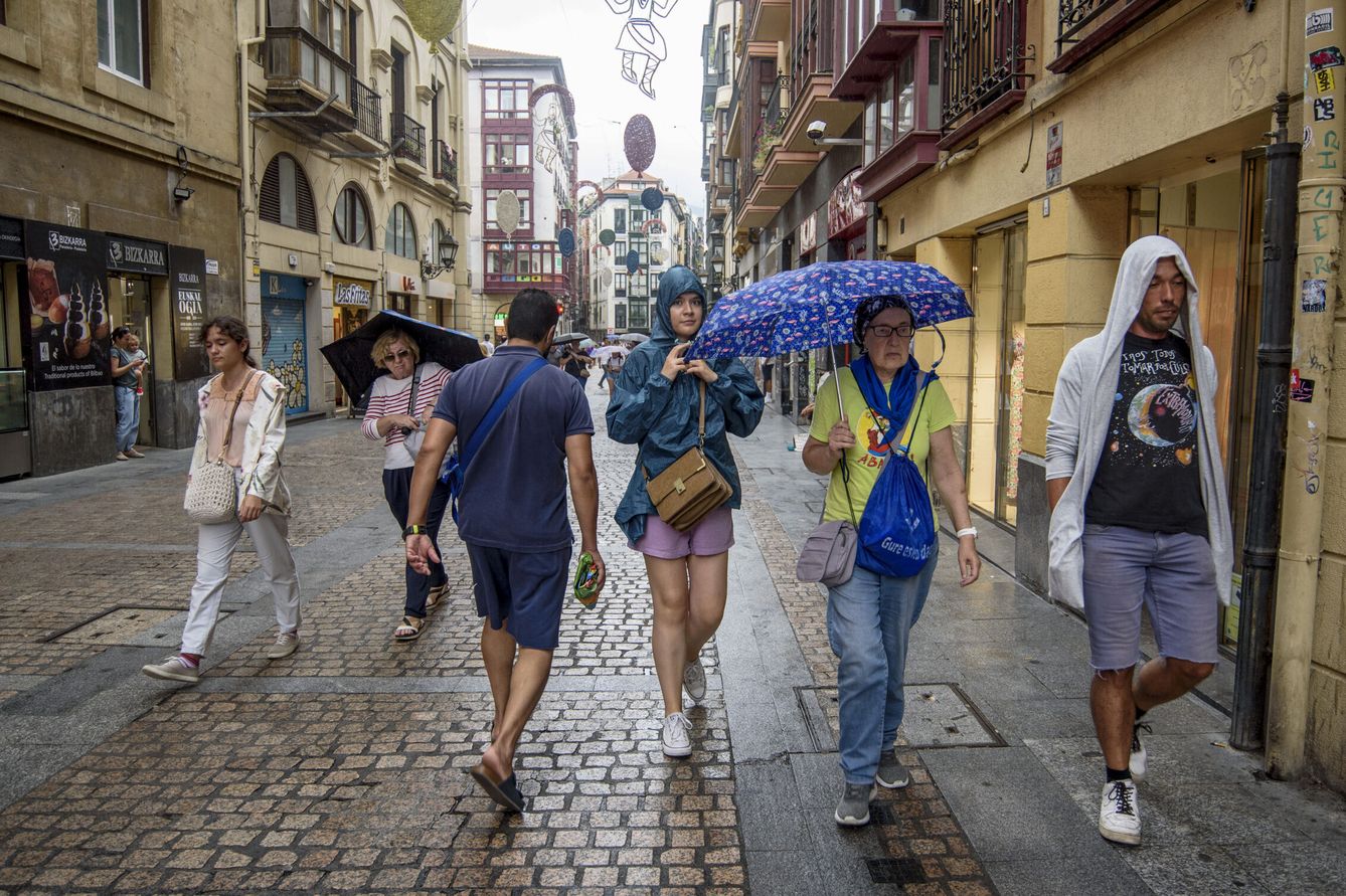 Viandantes se protegen de la lluvia en Bilbao este viernes. (EFE/Javier Zorrilla) 
