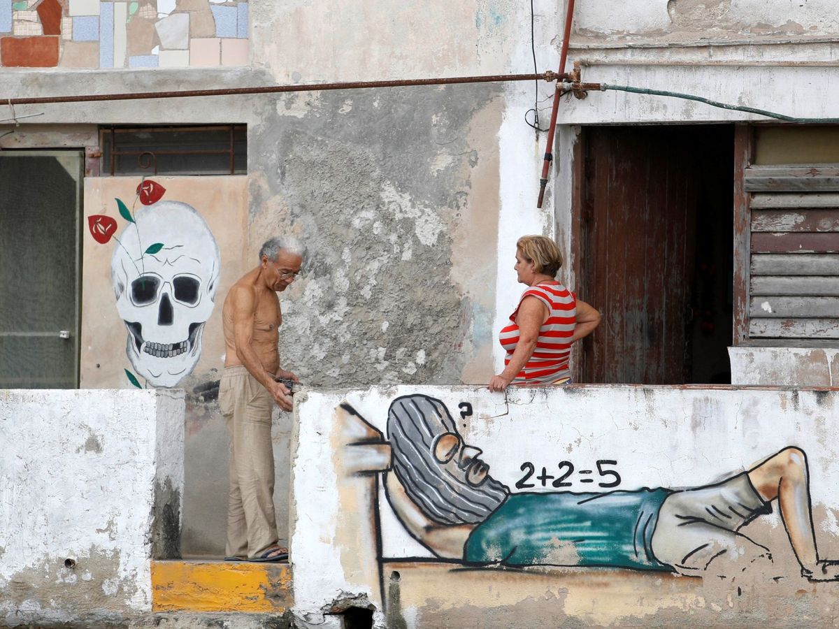 Foto:  Dos vecinos de La Habana conversan en un edificio pintado con graffiti. (EFE)