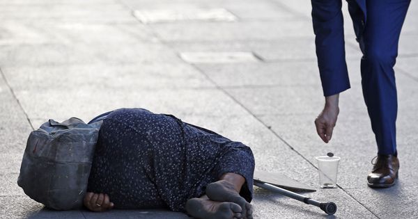 Foto: Un hombre echa una moneda a una mendiga en el centro de Madrid. (EFE)