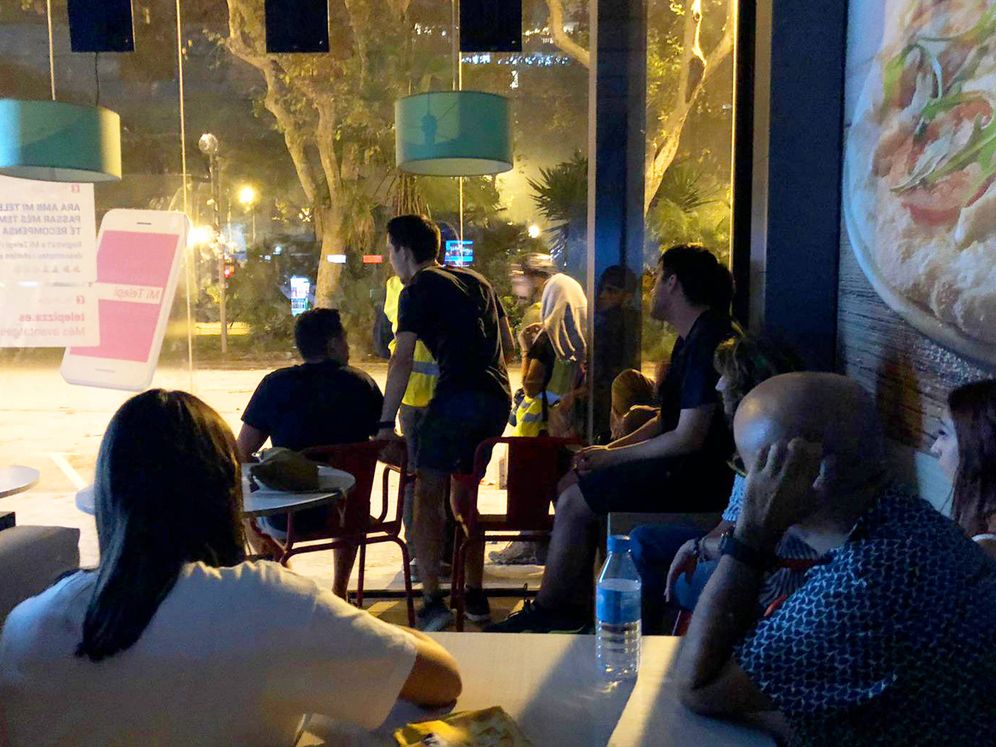 Foto: Atónitas, una decena de personas observan los disturbios desde el local de la pizzería. (A. V.)