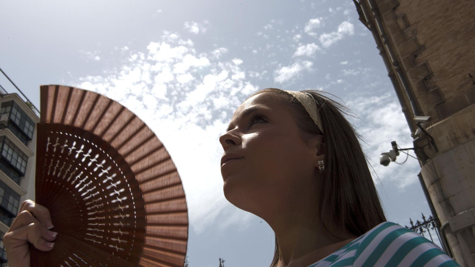 Foto: Una joven se refresca con un abanico  durante la ola de calor. (Efe)