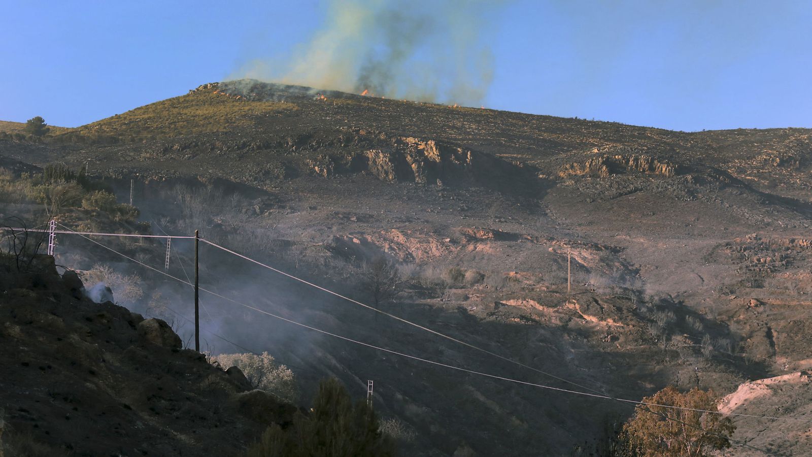 Foto: Parte del monte calcinado en Órgiva (Granada), donde se han desalojado a 550 personas de sus viviendas. (Efe) 
