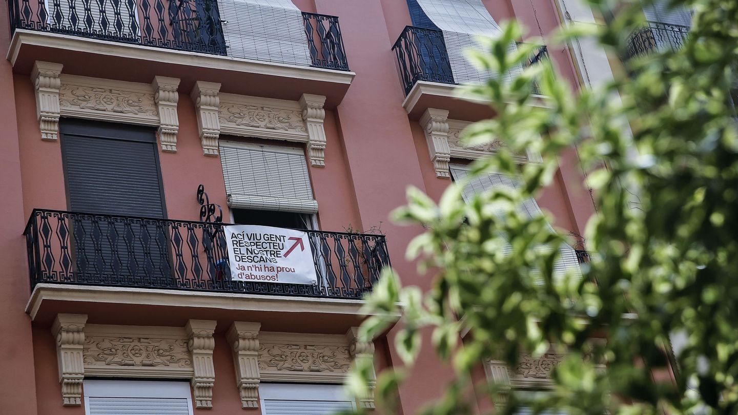 Unos vecinos reclaman, con una pancarta colgada en su balcón, respeto al descanso en un edifico Russafa. (EFE/Manuel Bruque)
