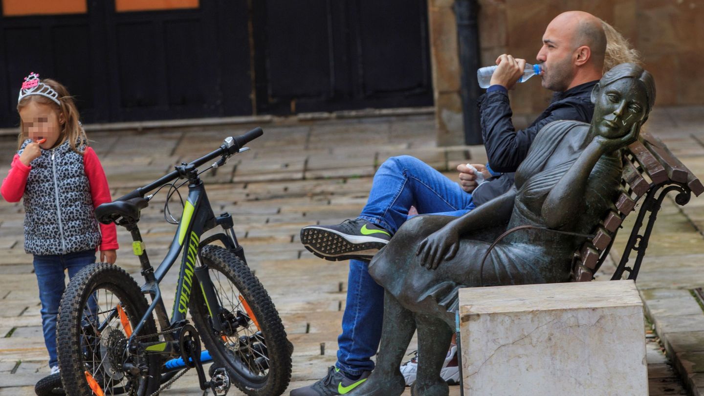 Un hombre descansa en un banco después de un paseo en bici con su hija en la plaza Trascorrales de Oviedo (EFE)