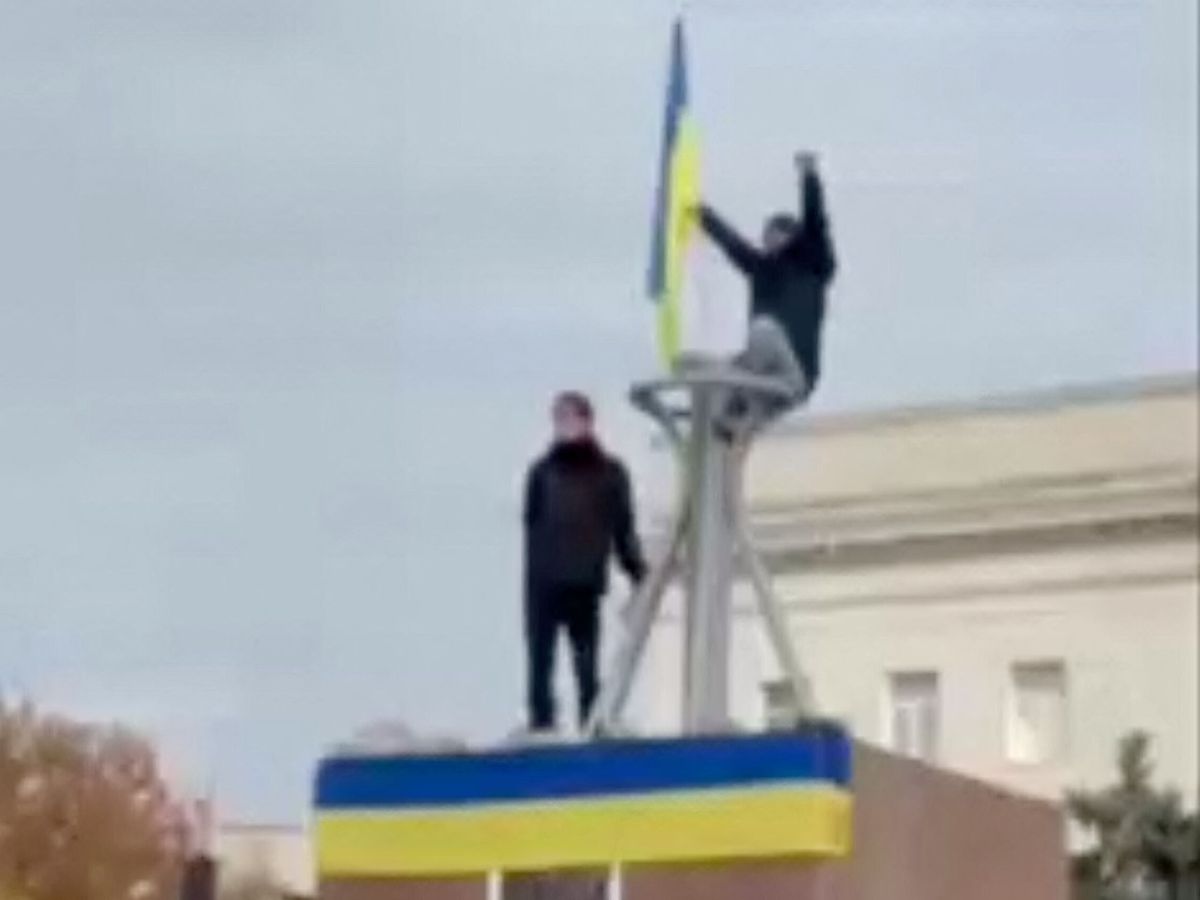 Foto: La gente aplaude y agita una bandera ucraniana sobre una estatua en la plaza de la Libertad en Jersón. (Reuters)