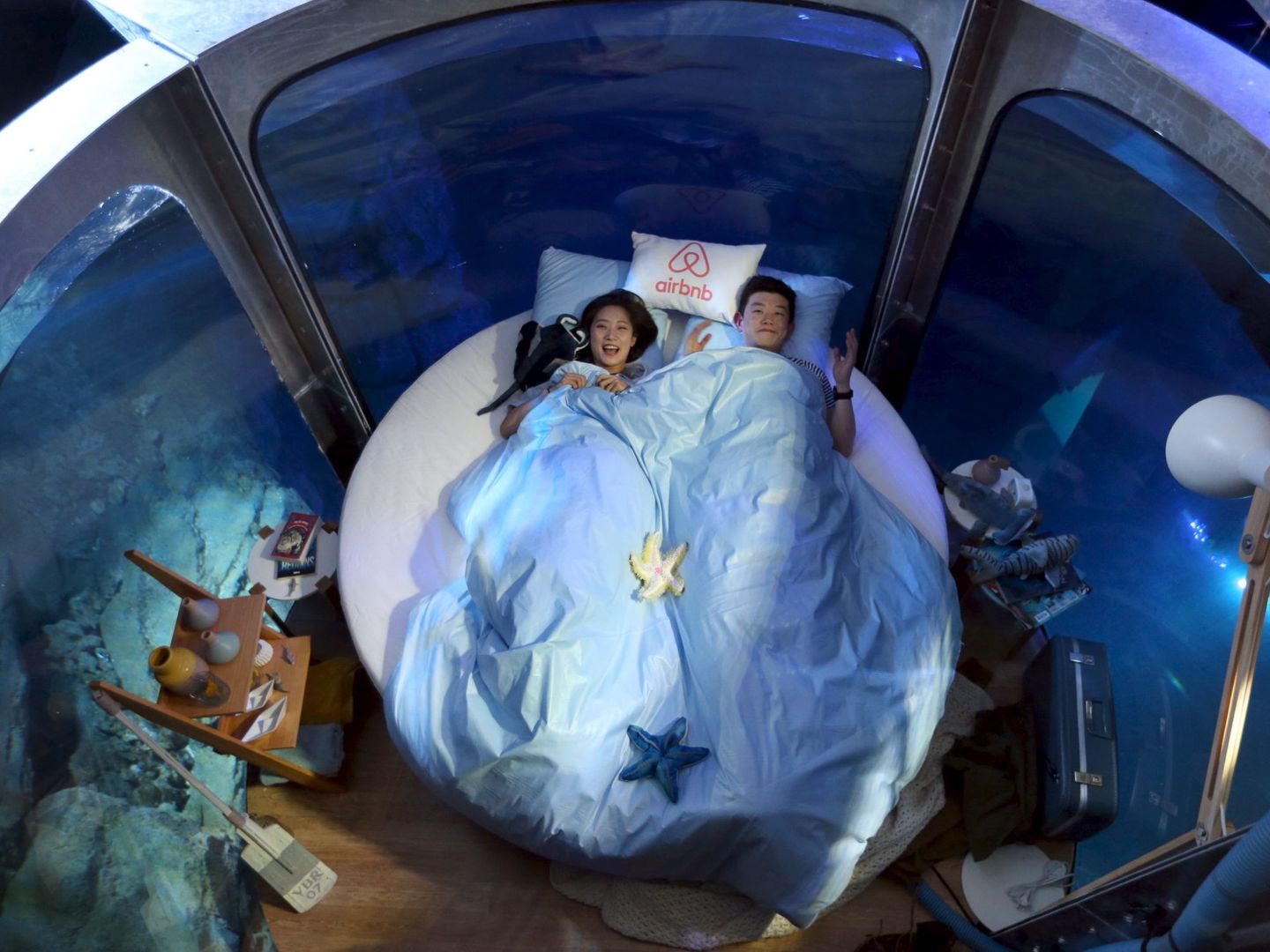 Los ganadores de un concurso de Airbnb durmiendo en una cápsula en el acuario de París (REUTERS)