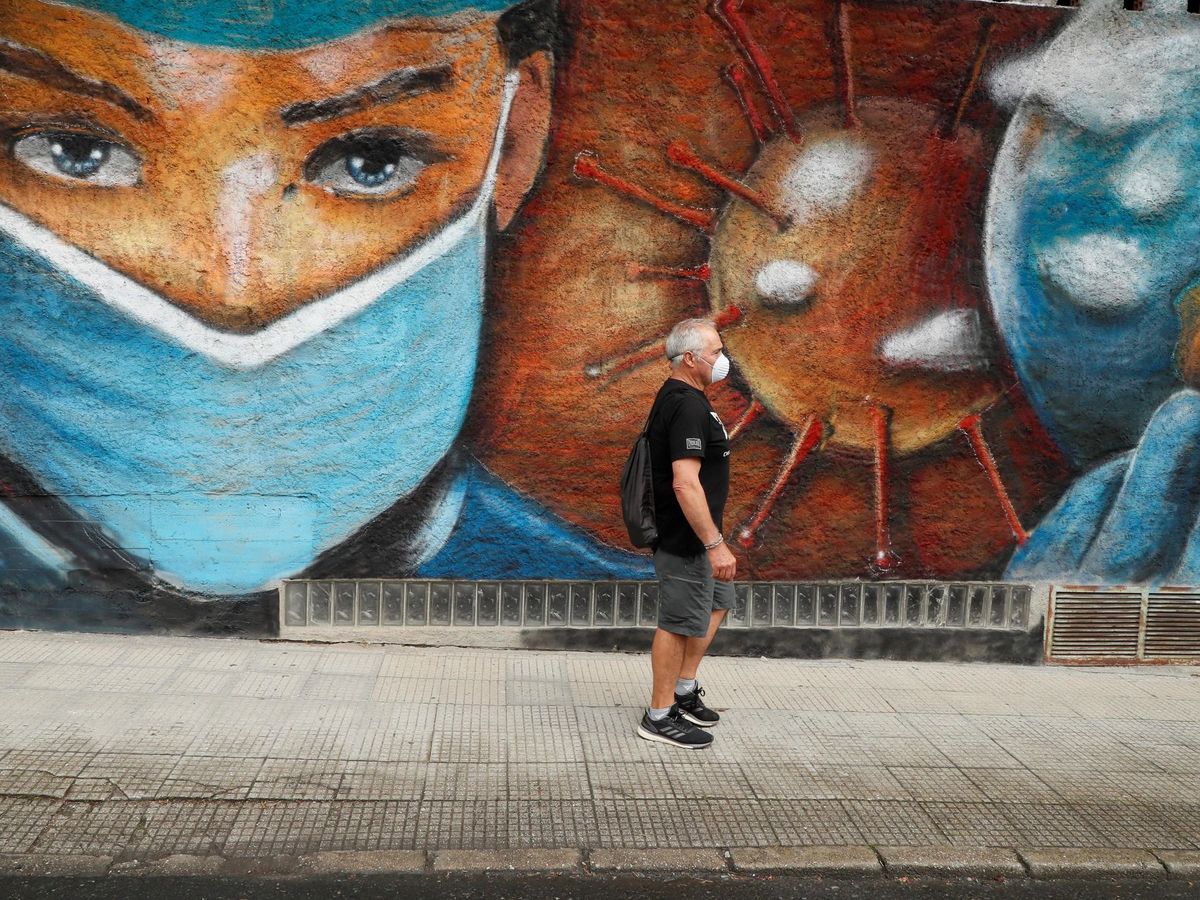 Foto: Un hombre camina junto a un mural en homenaje a los sanitarios en Melide. (EFE)
