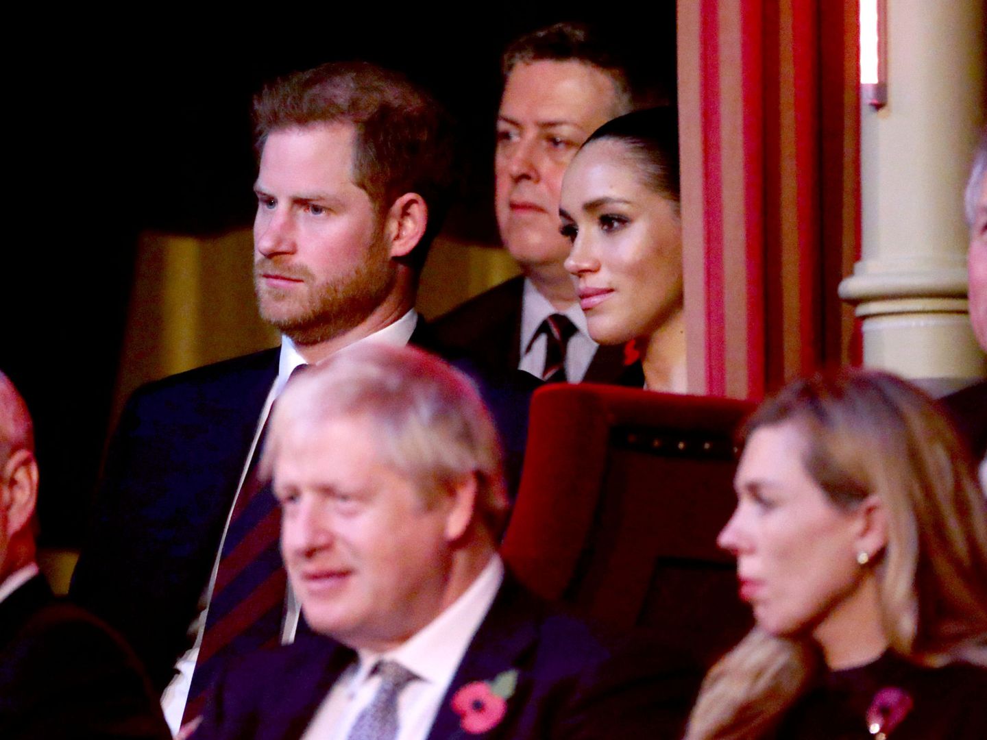 Harry y Meghan, con gesto serio, sentados detrás de Boris Johnson. (Reuters)