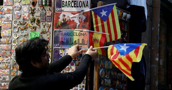Foto: Un empleado de una tienda coloca una estelada en Barcelona. (Reuters)
