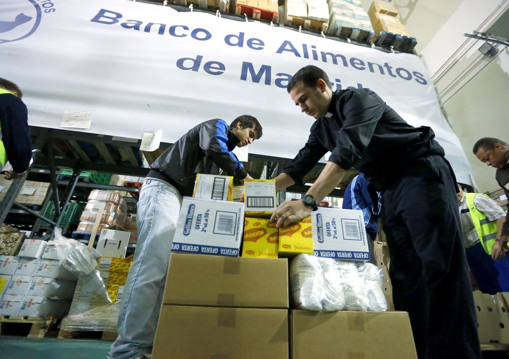 Foto: Un sacerdote acompañado de varios voluntarios trabaja en la fundación Banco de Alimentos de Madrid. (EFE)