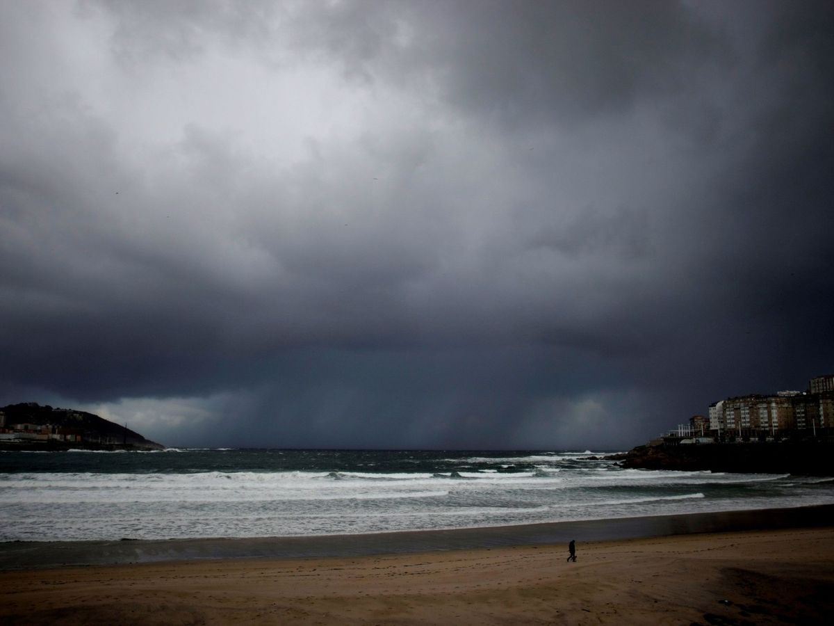 Foto: Un hombre pasea a su perro por la playa del Orzán en A Coruña, este viernes. (Efe)