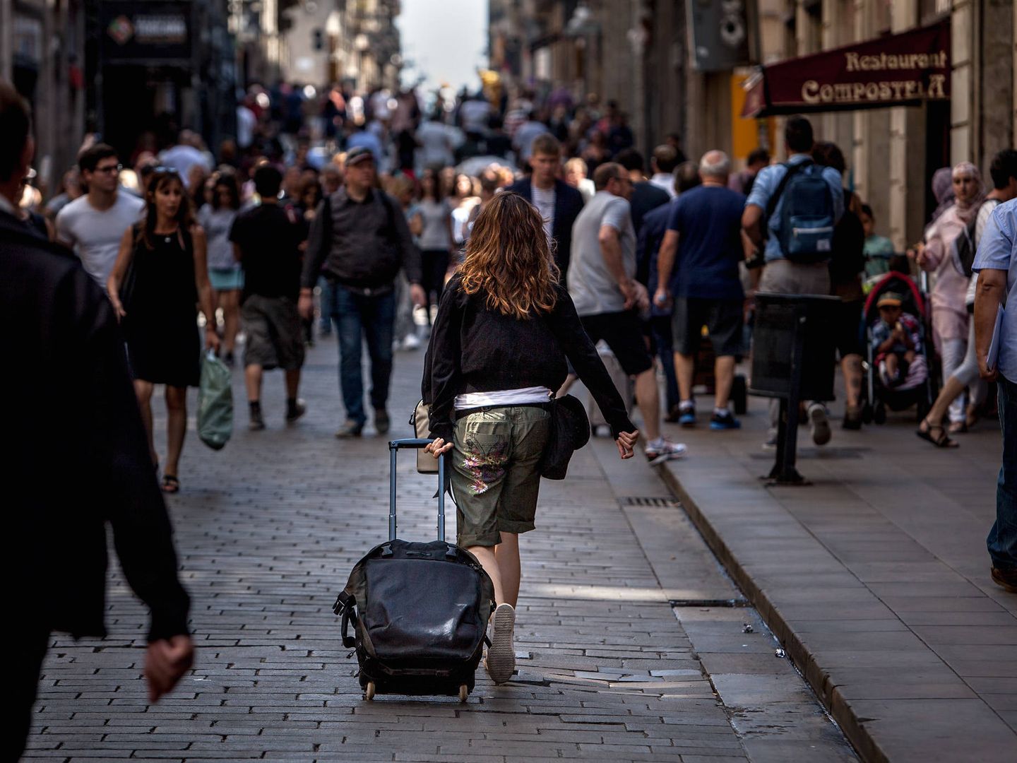 Una turista camina con una maleta por las calles de Barcelona. (EFE)