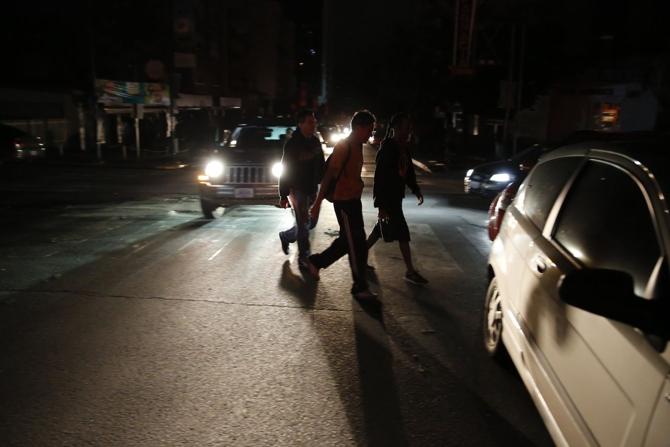 Varias personas cruzan una calle durante un apagón en Caracas en diciembre de 2013 (Reuters)