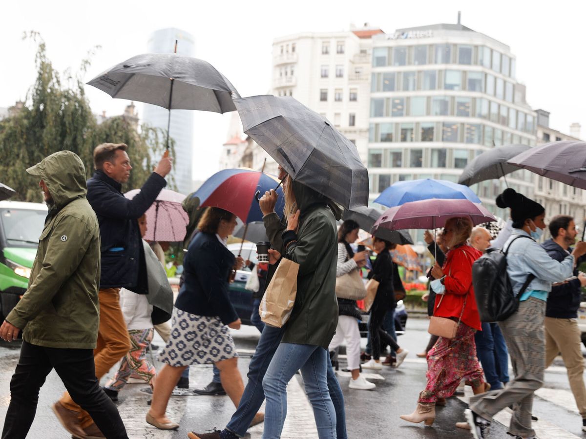 Foto: Varias personas pasean con paraguas en Bilbao. (EFE/Luis Tejido)