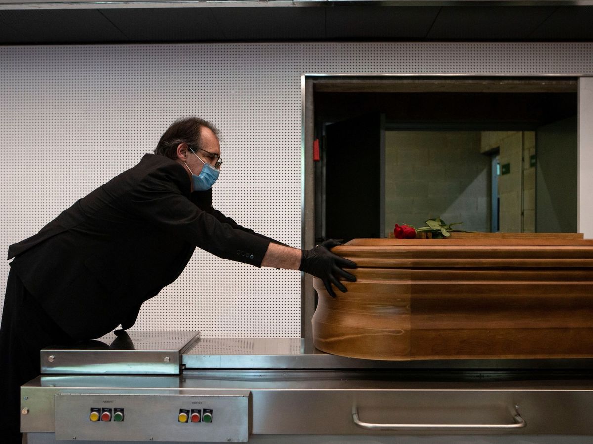 Foto: Un trabajador de la empresa funeraria Mémora introduce un ataúd en un horno crematorio. (EFE)
