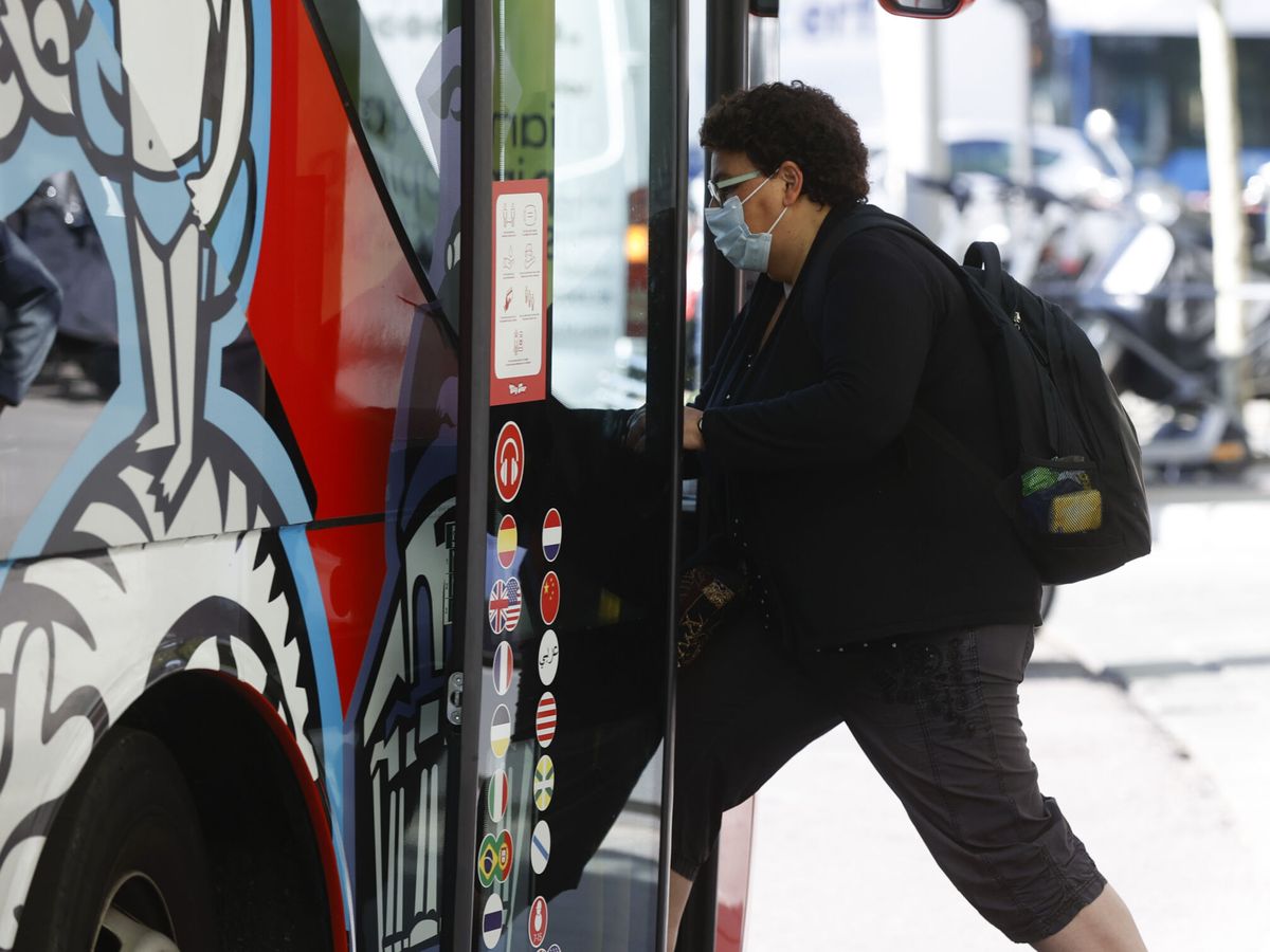 Foto: Una mujer con mascarilla sube a un autobús. (EFE/Juan Carlos Hidalgo)