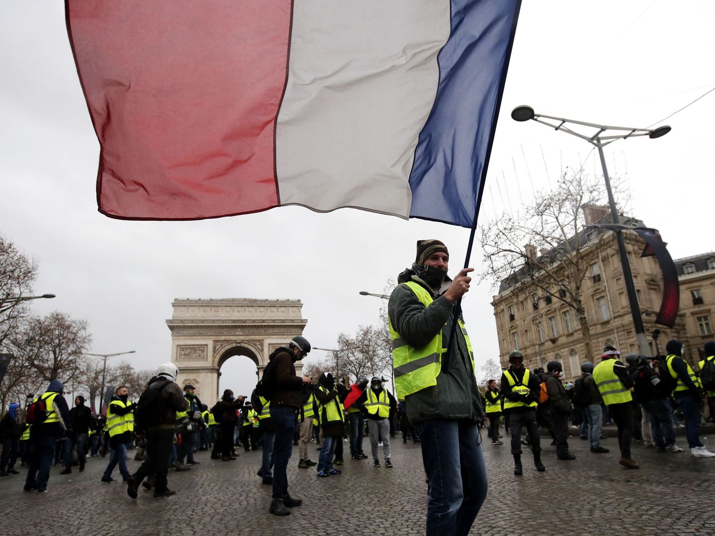  Un manifestante de los chalecos amarillos ondea una bandera tricolora francesa durante una manifestación en París. (EFE)