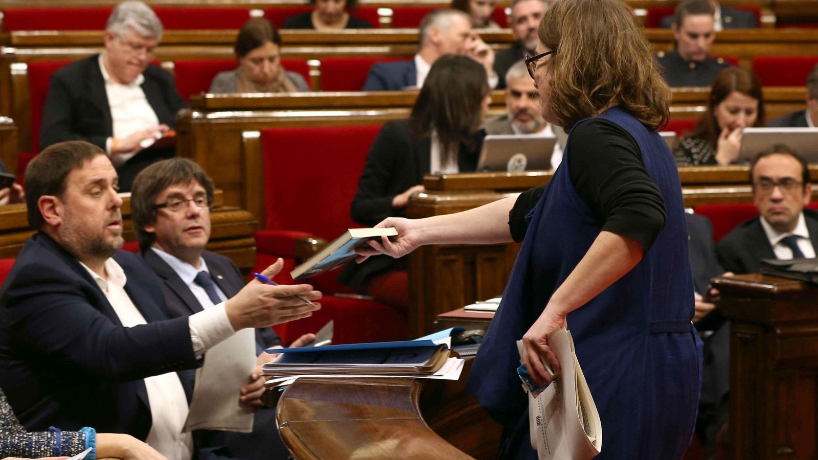 Foto: La diputada de la CUP Euilàlia Reguant le regala un libro al vicepresidente, Oriol Junqueras, durante el debate sobre los presupuestos en el Parlament. (EFE)