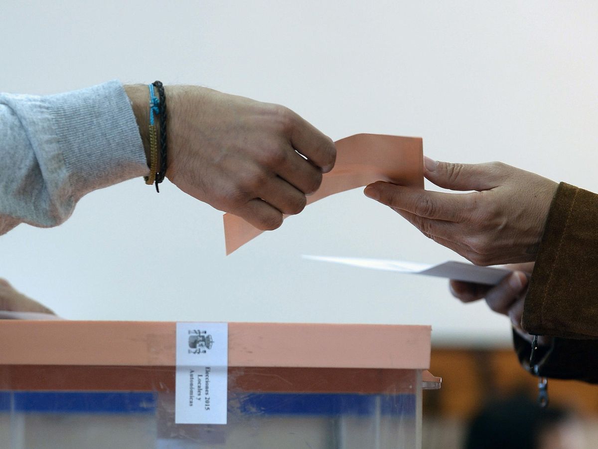 Foto: Detalle de las manos de una mujer entregando sus sobres en una mesa electoral. (EFE/Nacho Gallego)