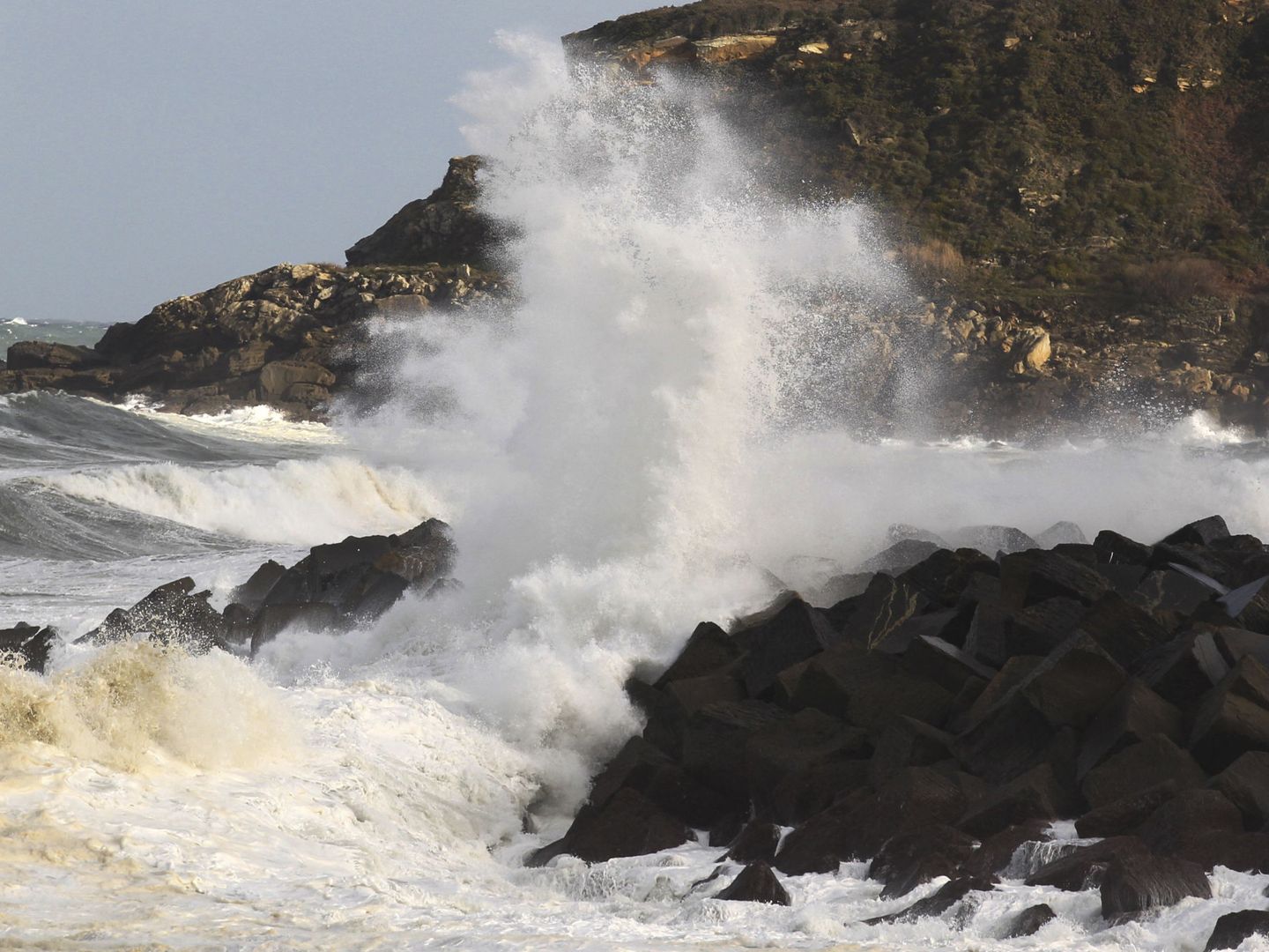 Una ola rompe contra el espigón que protege la playa de la Zurriola de San Sebastián. (EFE)