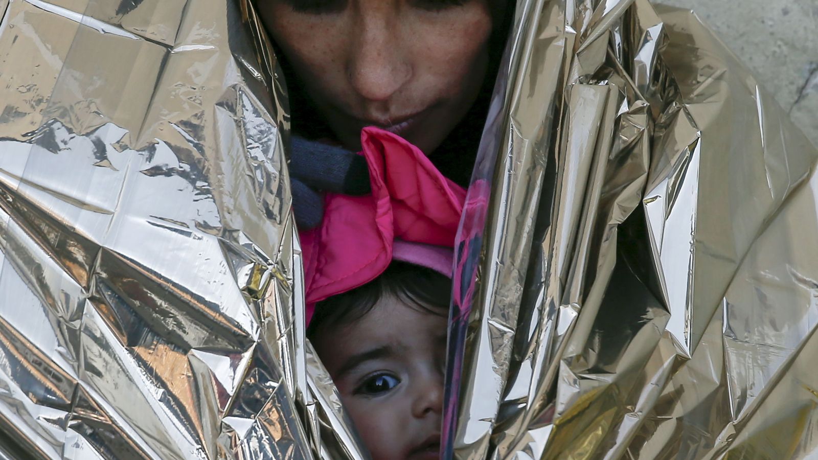 Foto: Una refugiada y su hija, envueltas en una manta térmica mientras esperan un tren a Croacia en la estación de Presevo, Serbia, el 20 de enero de 2016. (Reuters)